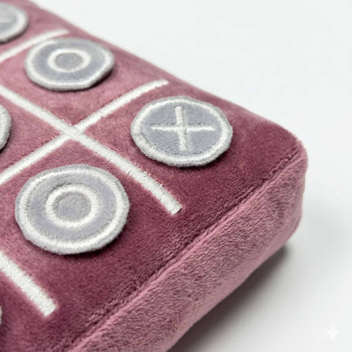 Close-up of the Heritage Pink velvet TicTac2Go pillow with embroidered O and X pieces